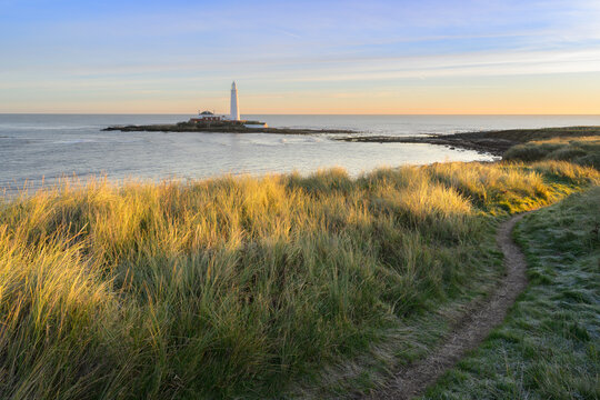 Peaceful footpath with view of St Mary's Island and Lighthouse on a beautiful sunny morning. Whitley Bay, North Tyneside, England, UK.