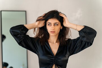 Woman posing in black satin dress holding her hair