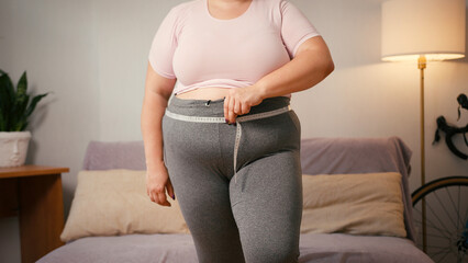 Plus size woman measures waist reacting to unsatisfactory result