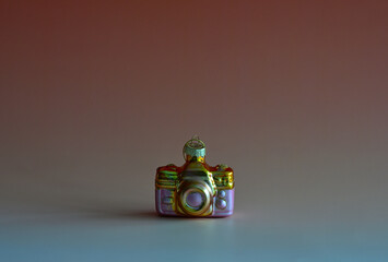 Weihnachtsschmuck in Form einer Kamera vor buntem Hintergrund