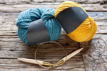 Blue and Yellow Yarn Balls with Knitting Needle on Rustic Wooden Surface