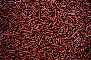 Full frame overhead background of brown, stick-shaped chocolate sprinkles