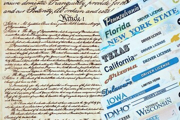 Naklejka premium Big amount of driving licenses from different USA states on constitution page. Stack of driving license specimen cards