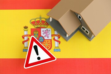 Residential house with alert sign on Spanish flag close up. Concept of Squatting in Spain. Okupas problem