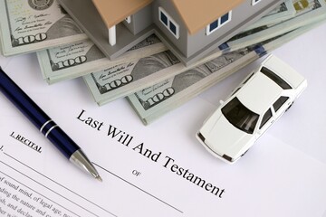 Generic toy house with US dollar bills, car and Last will and testament with pen on table close up