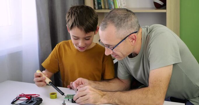 Family works on stem project at home. Father guides boy through electronics task. hands on learning and creative teamwork. Stem activity develops skills and supports steady interest in technology.