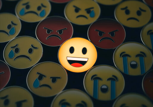 un emoji feliz en medio de muchos emojis tristes y enojados, met&aacute;fora de las personas positivas.