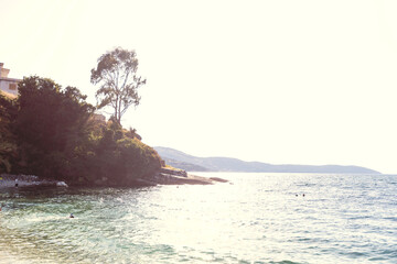 Calm turquoise waters shimmer under golden sunlight along a secluded rocky shore