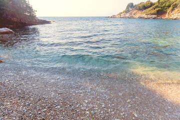 Close up of clear water washing over pebble beach and rocky cove