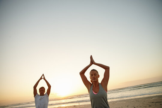 Meditation, sunset and zen with couple on beach together for balance or mindfulness routine. Awareness, fitness and mockup space with calm people outdoor on coast for holistic health or wellness - Powered by Adobe