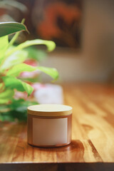 Aromatic Candle with Wooden Wick on Natural Wooden Surface and Green Foliage Background
