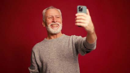Stylish smiling happy senior man holding mobile phone taking photo handsome blogger showing thumb up