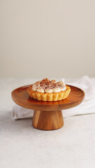 Individual Tiramisu Tart with Whipped Cream and Cocoa Dusting on Wooden Stand