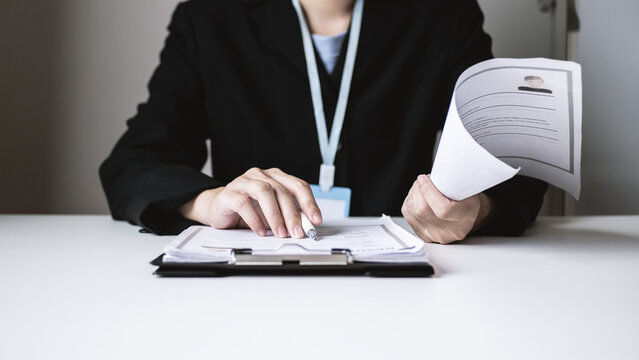 Businesswoman reading resume of new job applicant, reviewing history and evaluating documents before interviewing new employee. Recruitment concept