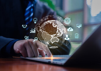 A businessman using a laptop with a digital global interface and business analytics icons, representing innovation, global strategy, and modern technology solutions for data-driven decision making.