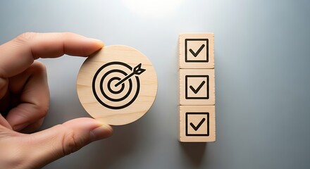 Hand holding wooden target next to checklist boxes on a gray surface