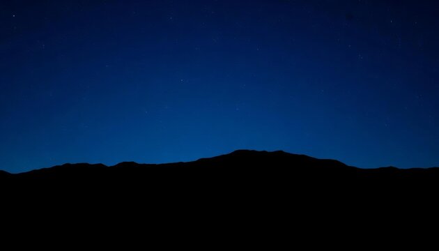 Deep blue gradient night sky over dark mountain silhouettes, speckled with stars,  evening,  serene