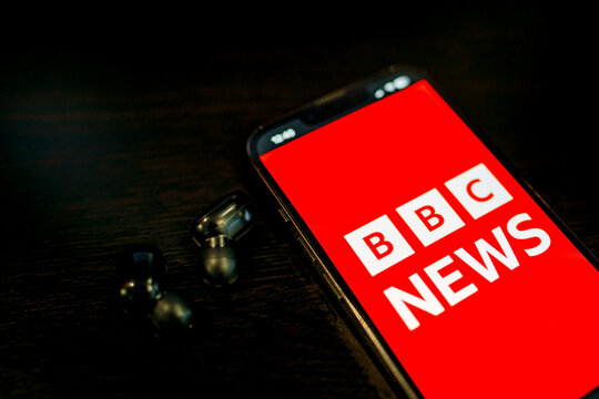 Moscow, Russia - 27.11.2025: BBC news on my phone, and my headphones are lying on the table