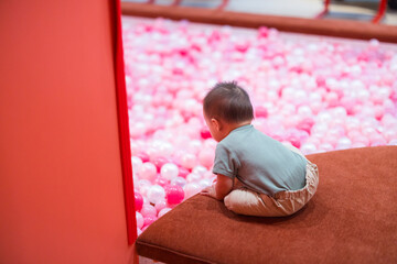 Cute baby playing happily in pink ball pool