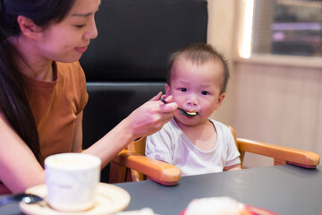 Young mother feeding baby inside sushi shop