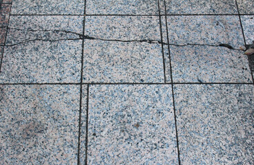 Texture of cracked square paving tile. Pattern of beige and gray tiles in the street. Concrete pavers close up background.