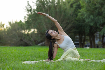 Woman doing stretching exercises outdoors in park grass