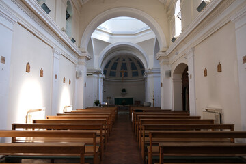 Empty Wooden Pews Lining Church Nave Leading Towards Apse and Crucifix with Sunlight Streaming Through Windows