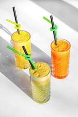 Three Refreshing Citrus Juices or Smoothies with Straws on White Background