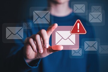 A person points to an email icon with a red exclamation mark, signifying a spam or phishing email, highlighting the importance of cybersecurity awareness