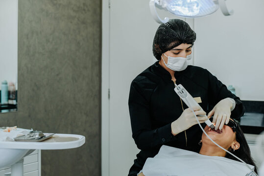 Dental professional performing intraoral scanning on patient using digital scanner in clean, modern clinic environment.