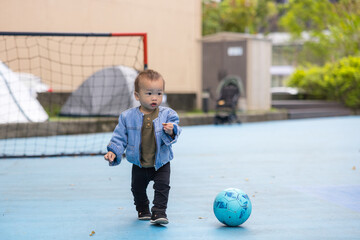 Adorable toddler kicking soccer ball outside