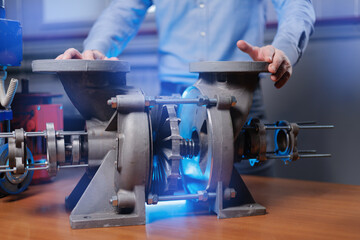 Engineer demonstrating industrial pump mechanism with turbine, blue light effect