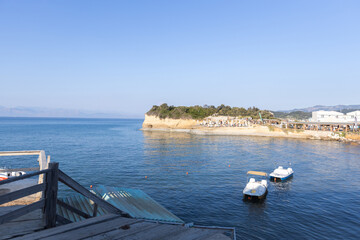Paddle boats on clear sea water near coastal cliffs and sandy beach