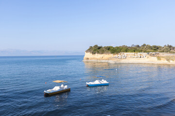Paddle boats on clear sea water near coastal cliffs and sandy beach