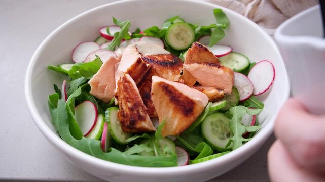 Salad with grilled salmon, cucumber, radish, capers, arugula and tahini dressing.