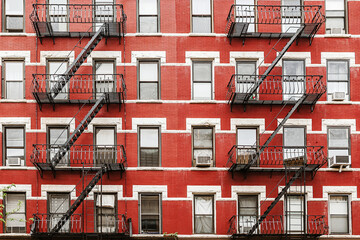 Red brick apartment building with black fire escapes in a classic urban American city neighborhood.
