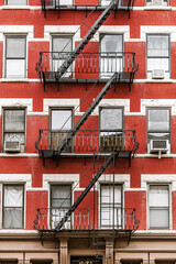 New York red brick building with fire escapes and classic urban architecture.