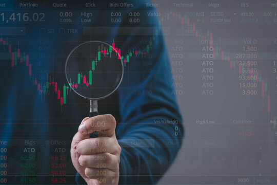 A person analyzing stock charts with a magnifying glass, symbolizing market research, financial analysis, investment strategy, and data-driven decision-making in the trading industry. - Powered by Adobe