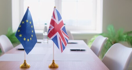 UK and EU flags sit on table during office meeting or negotiation on brexit, reflecting political agreement, international communication, addressing brexit issues in a focused business environment.