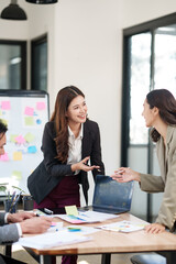 Group of Asian businesspeople sits down for a business investment planning meeting.