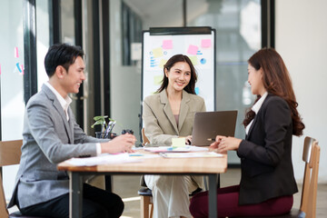 Group of Asian businesspeople sits down for a business investment planning meeting.