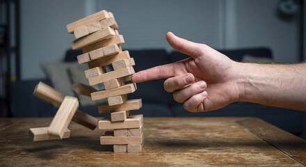Hand stopping falling dominoes representing crisis management and intervention.