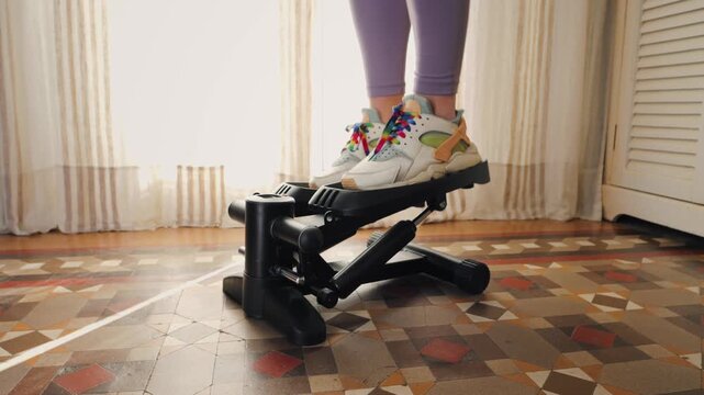 Woman doing exercises on stepper at home, Close up of legs with sneakers. 