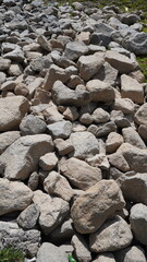 Close-up of a large pile of gray and beige rocks of varying sizes on the ground, roughness concept.
