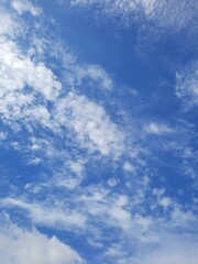 Obraz premium Scattered white clouds floating in a bright blue sky on a clear day