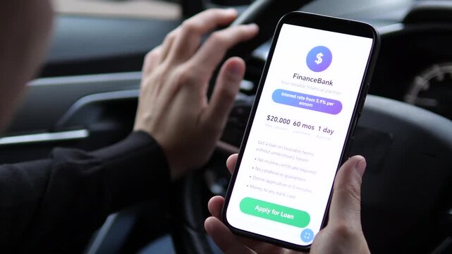 Closeup of a mans hands in a parked car carefully reviewing the terms and conditions for an online loan offer on his smartphone. This contemplative moment captures the serious consideration behind