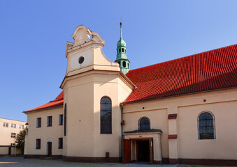 Naklejka premium Panoramic Front Facade of Red Brick Church with Yellow Walls. Roman Catholic Church at Wawrzyńca Street in Gniezno, Greater Poland Voivodeship, Poland