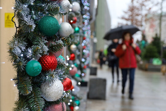 New Year decorations in rainy city, Christmas balls on a street on blurred background of people
