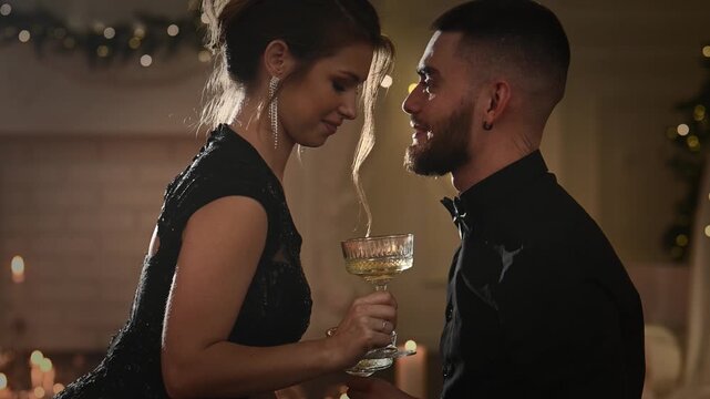 A young couple in love celebrates Christmas and New Year's in a romantic atmosphere with champagne, toasting and making wishes. A kiss on the shoulder on brotherhood