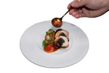 A close-up shot of a gourmet dish being expertly plated and sauced. A chef's hand delicately garnishes the meal with sauce